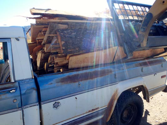 Forklift placing slabwood bundle in  pickup truck.