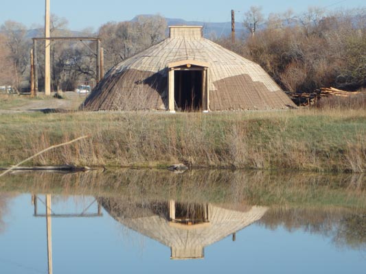 Earthlodge reflected in pond.