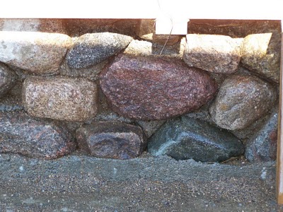 Slipform stone sand washed away revealing stone wall.