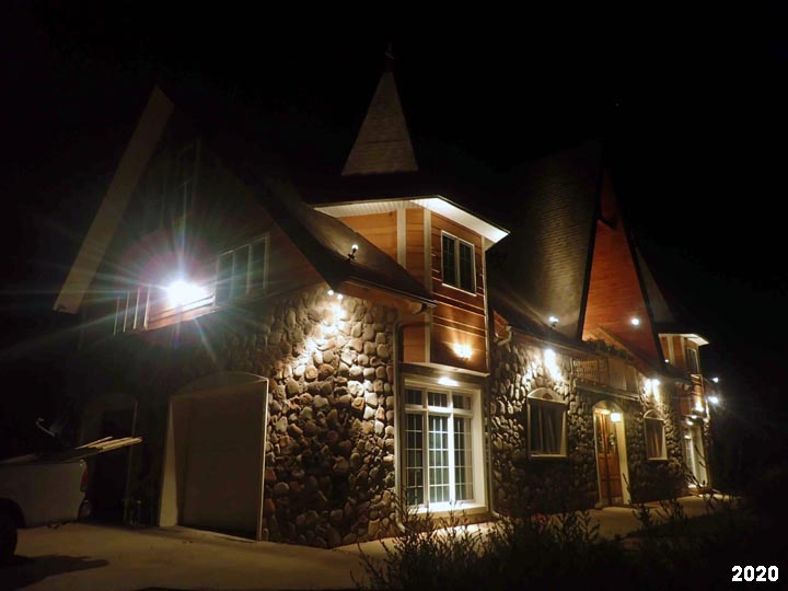 Gruber slipform stone masonry home with night lighting.