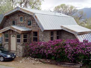 Barn style slipform stone home with lilacs.