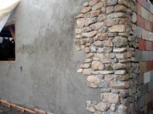 Stucco over cinderblock to stone corner.